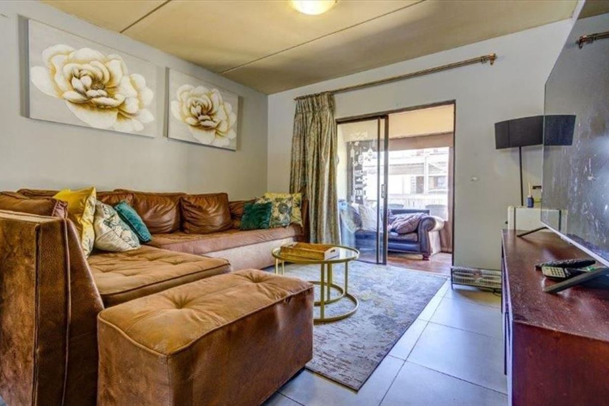 A living room featuring tiled flooring and a sliding glass door providing access to an outdoor patio area.