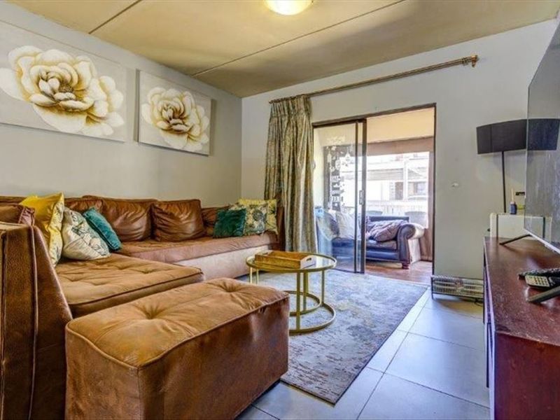 A living room featuring tiled flooring and a sliding glass door providing access to an outdoor patio area.