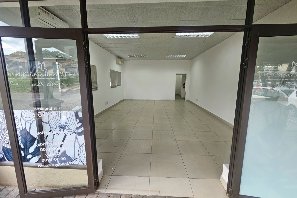 A vacant commercial entry space featuring tiled flooring, a suspended ceiling with recessed lighting, and large aluminium-framed glass doors.