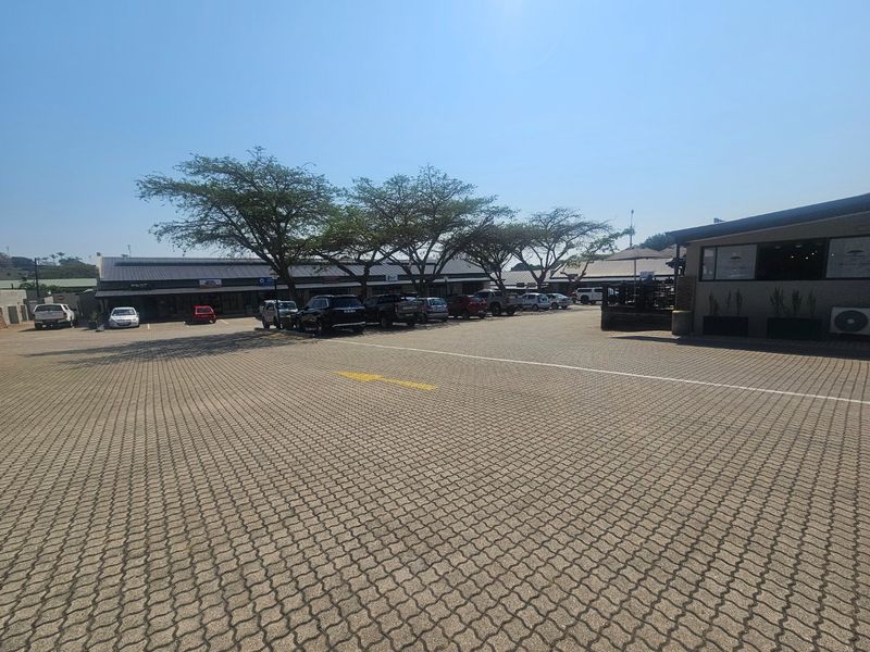 A wide-angle view of a commercial property featuring a paved parking lot and building facades with metal roofing.
