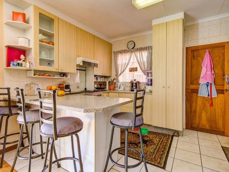 A functional kitchen featuring laminate cabinetry, granite countertops with a breakfast bar, tiled backsplash, and tiled flooring, providing a practical cooking and dining space.