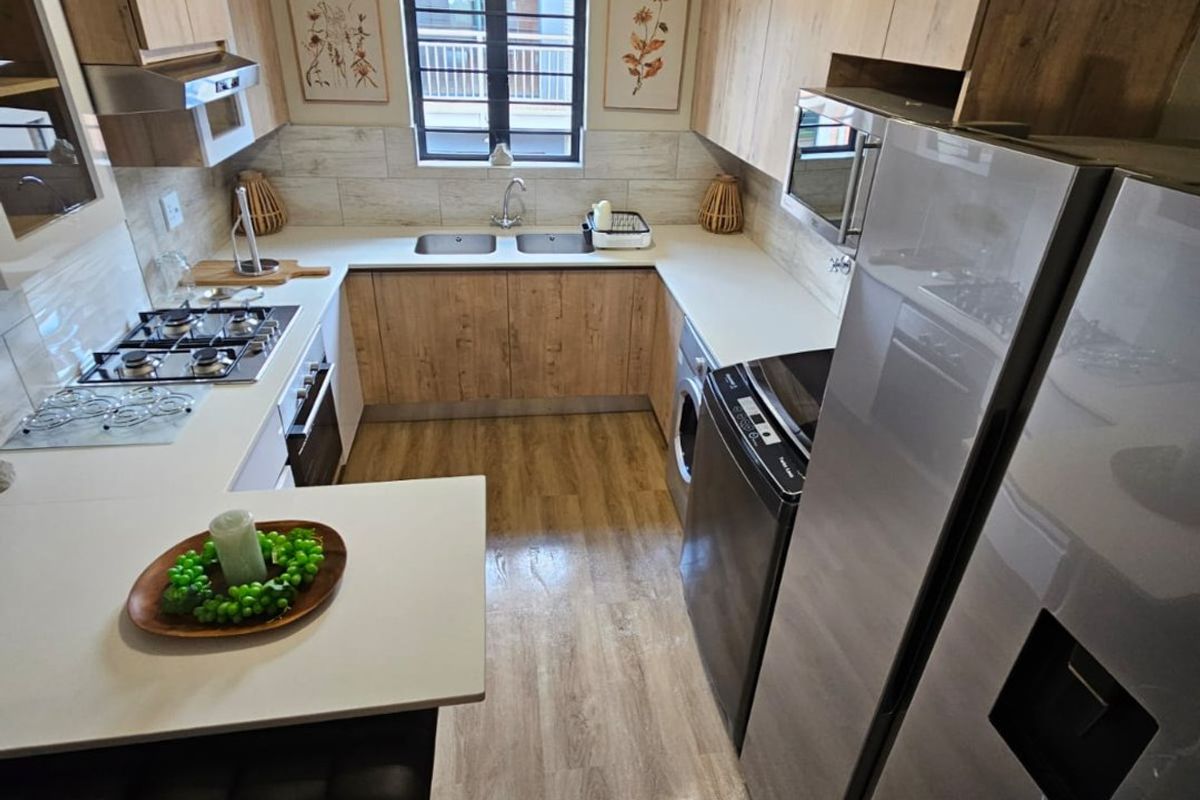 Modern U-shaped kitchen featuring wood-look cabinetry, laminate countertops, integrated gas hob, built-in oven, and durable laminate flooring with a functional layout.