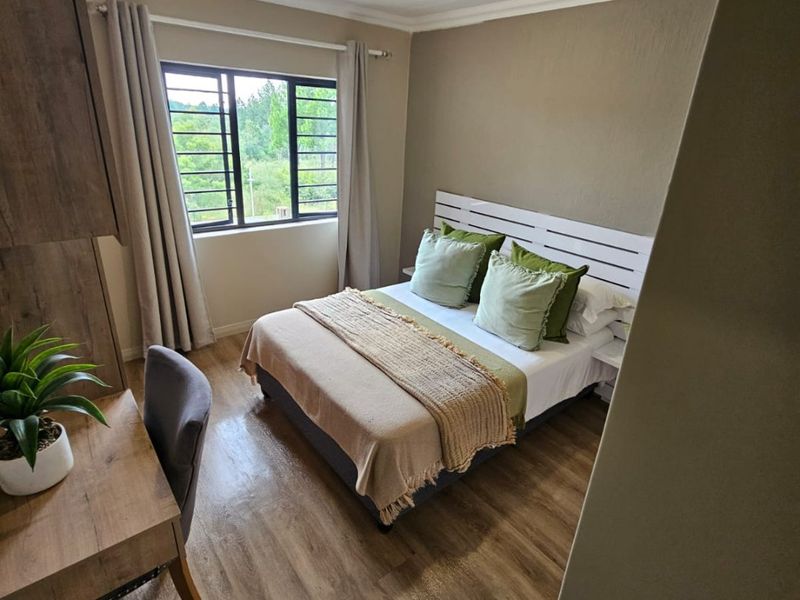 A well-maintained bedroom featuring laminate flooring, coving, and a window with security bars, offering a clean and functional living space.