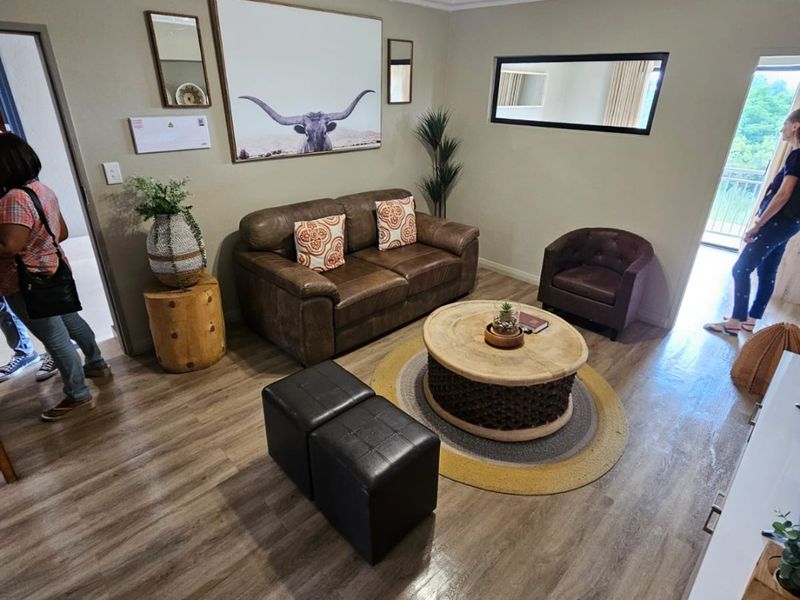 A well-maintained living room featuring durable laminate flooring, cove cornicing, and a modern ceiling-mounted spotlight fixture, offering a comfortable and functional living space.