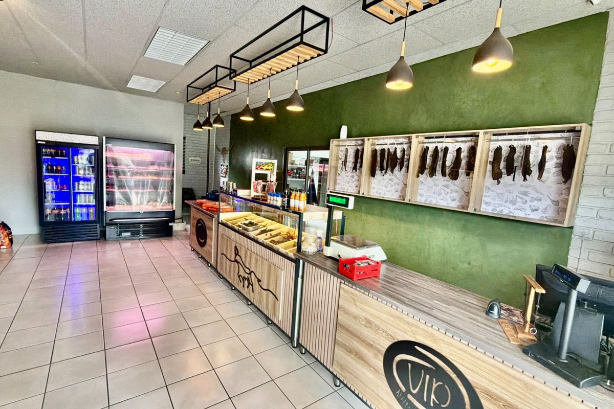 A well-maintained commercial retail space featuring a service counter, integrated display refrigeration, and modern industrial-style lighting fixtures.