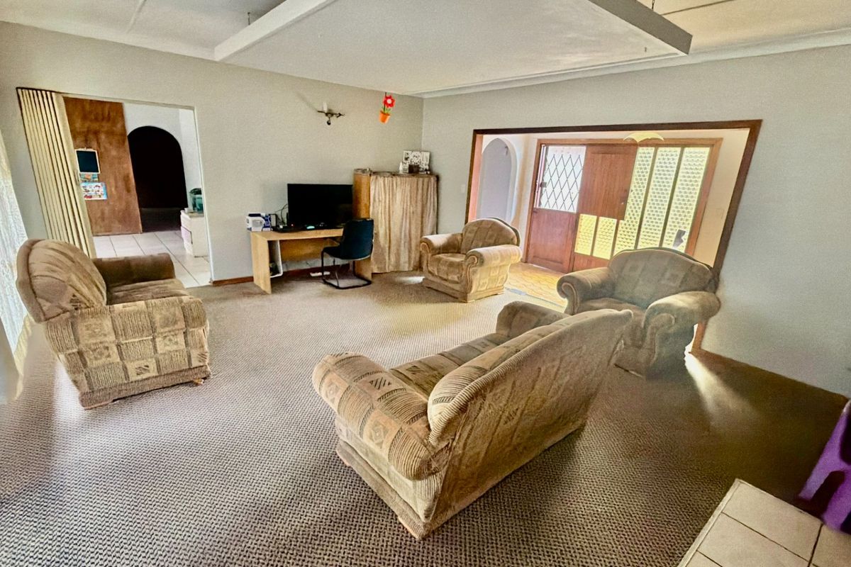 Spacious living area featuring carpeted flooring and a recessed ceiling detail, providing a functional layout with access to adjacent rooms.