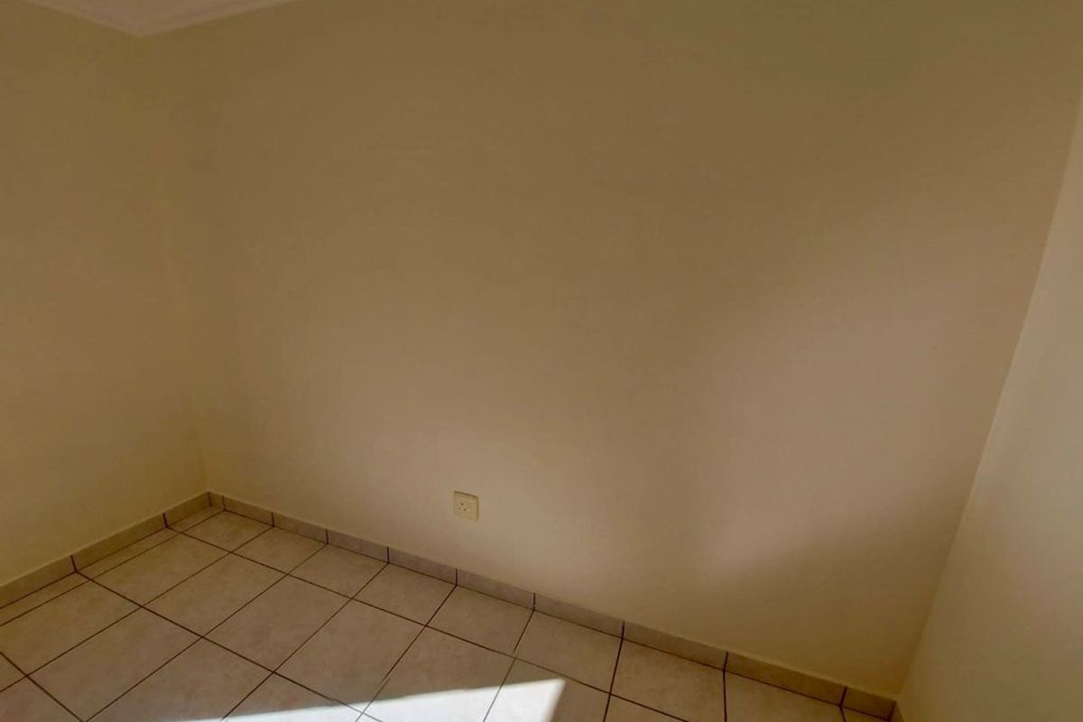 An empty bedroom featuring neutral wall paint and tiled flooring, providing a blank canvas for personalization.