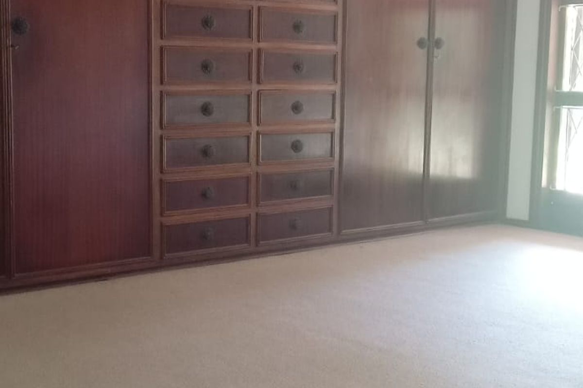 Spacious bedroom featuring extensive wall-to-wall built-in wooden cabinetry, a ceiling fan, and neutral carpeting.