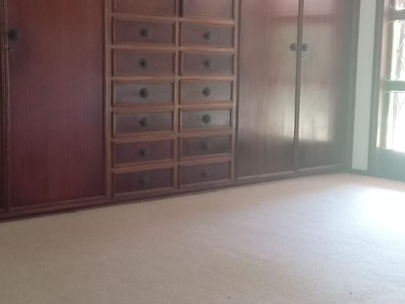 Spacious bedroom featuring extensive wall-to-wall built-in wooden cabinetry, a ceiling fan, and neutral carpeting.