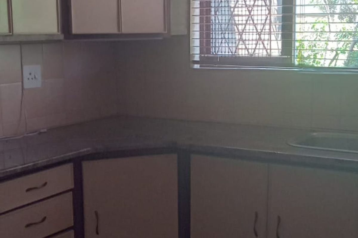 A dated kitchen featuring laminate cabinetry, tiled flooring, and a stainless steel sink, offering potential for a modern renovation.