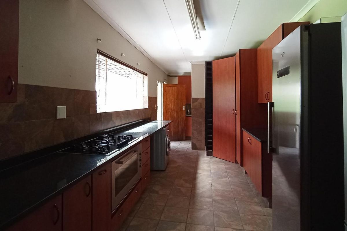 A functional kitchen featuring dark wood cabinetry, granite countertops, a gas hob, and built-in oven with tiled flooring and backsplash.