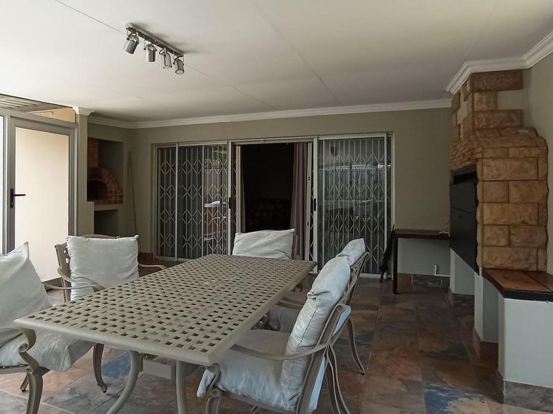 Covered patio area featuring a built-in braai with stone cladding, tiled flooring, and sliding door access to the main living space.