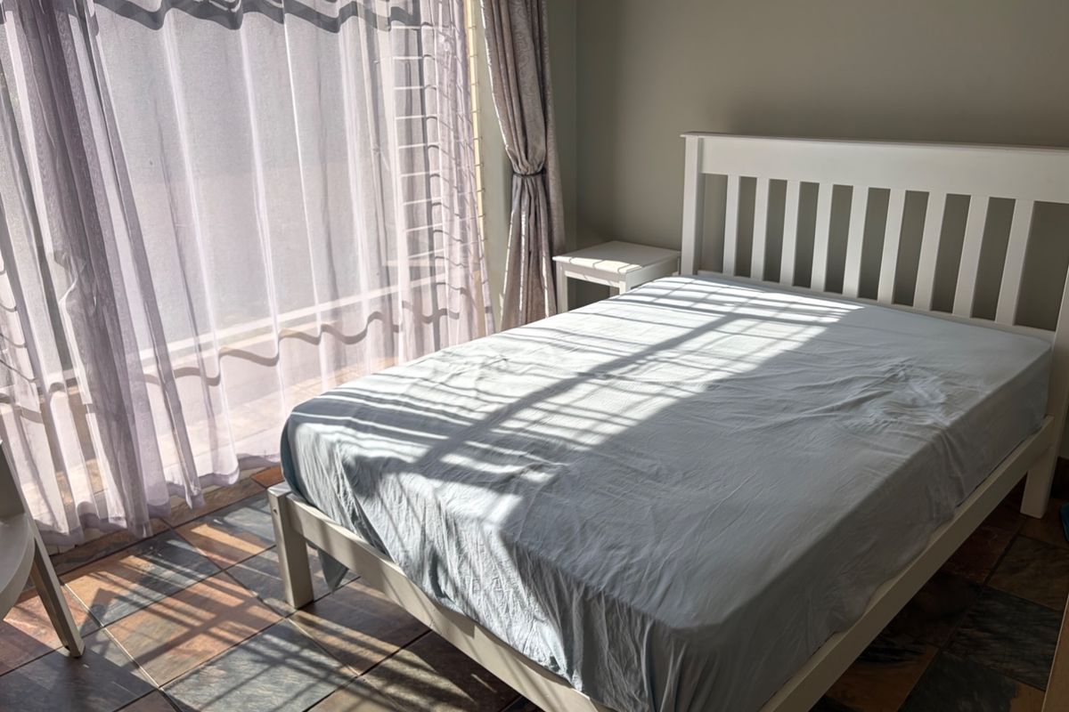 A bedroom featuring tiled flooring and a large sliding glass door that allows for natural light.