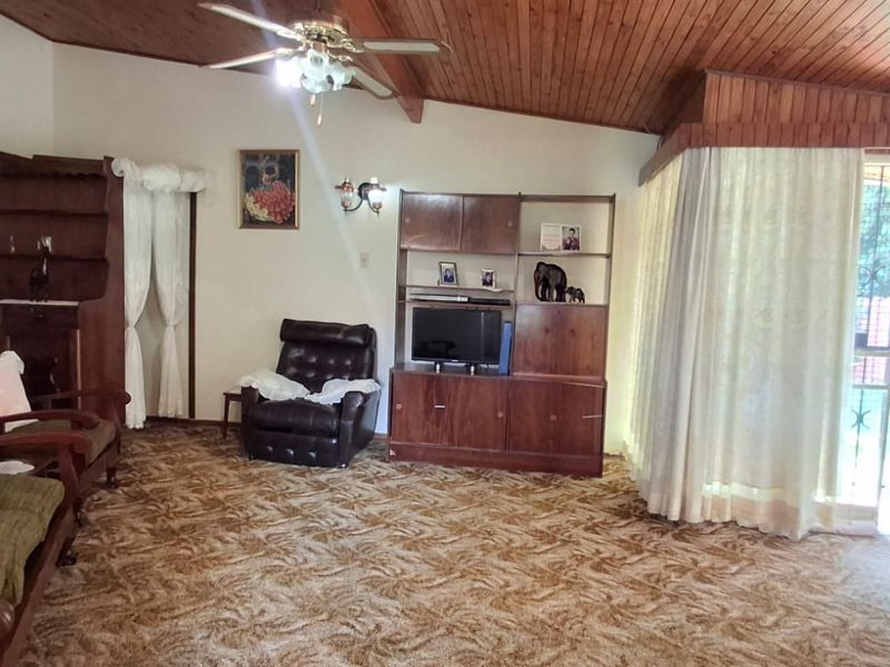 Spacious living room featuring a vaulted timber-clad ceiling, ceiling fan, and direct access to the outdoor area through a sliding glass door.
