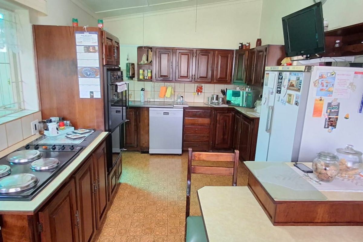 A functional kitchen featuring traditional wooden cabinetry, a built-in oven, electric hob, and tiled backsplash, offering a classic layout with ample storage space.