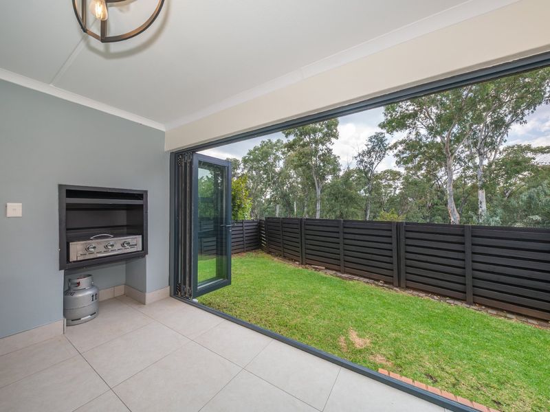 Covered patio featuring a built-in braai, large stacking doors, and direct access to a private garden area.
