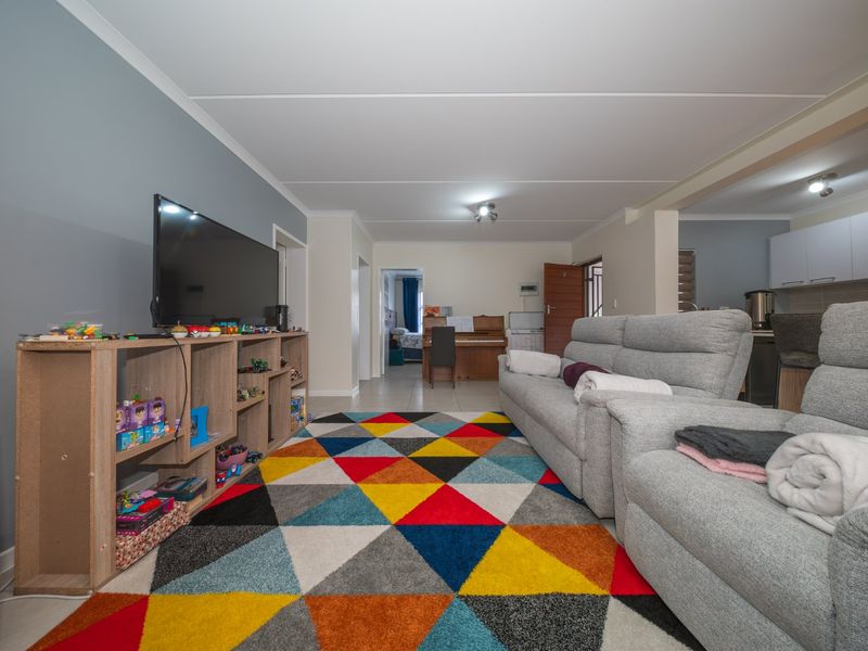 An open-plan living area featuring tiled flooring, neutral wall tones, and a connected kitchen space with modern cabinetry.