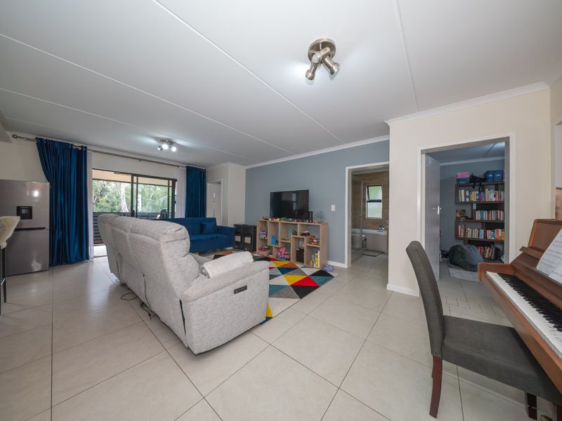 Spacious open-plan living area featuring neutral tiled flooring, modern ceiling lighting, and direct access to an outdoor patio through sliding glass doors.