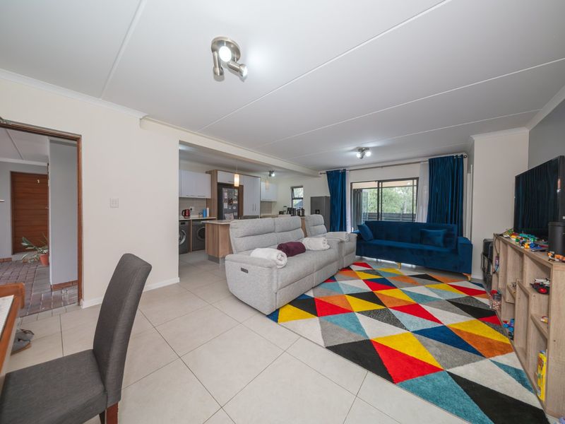 Spacious open-plan living area featuring tiled floors, a modern kitchen with island, and sliding doors leading to an outdoor space.