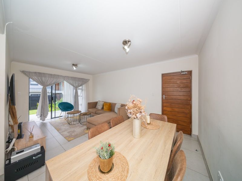 Open-plan living and dining area featuring tiled flooring, neutral walls, and a sliding glass door providing access to the outdoor space.