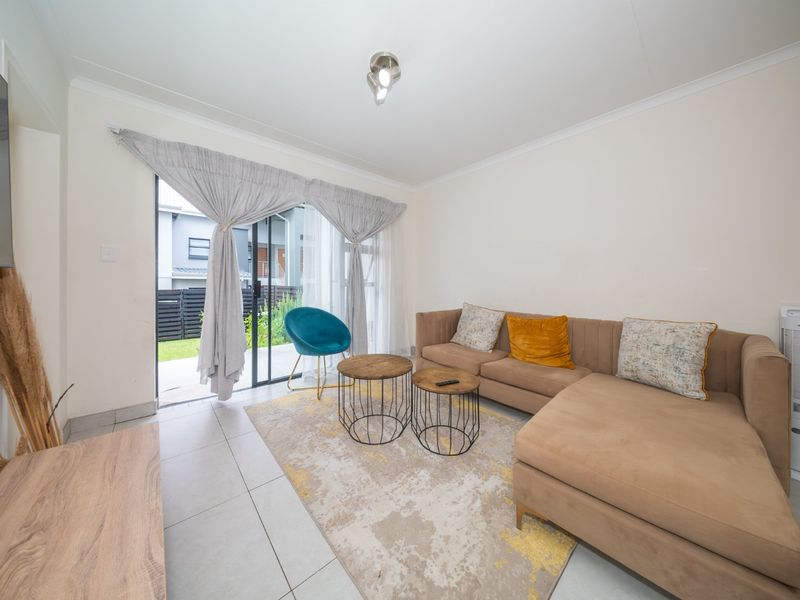A bright living room featuring tiled flooring and a sliding glass door providing direct access to the outdoor area.