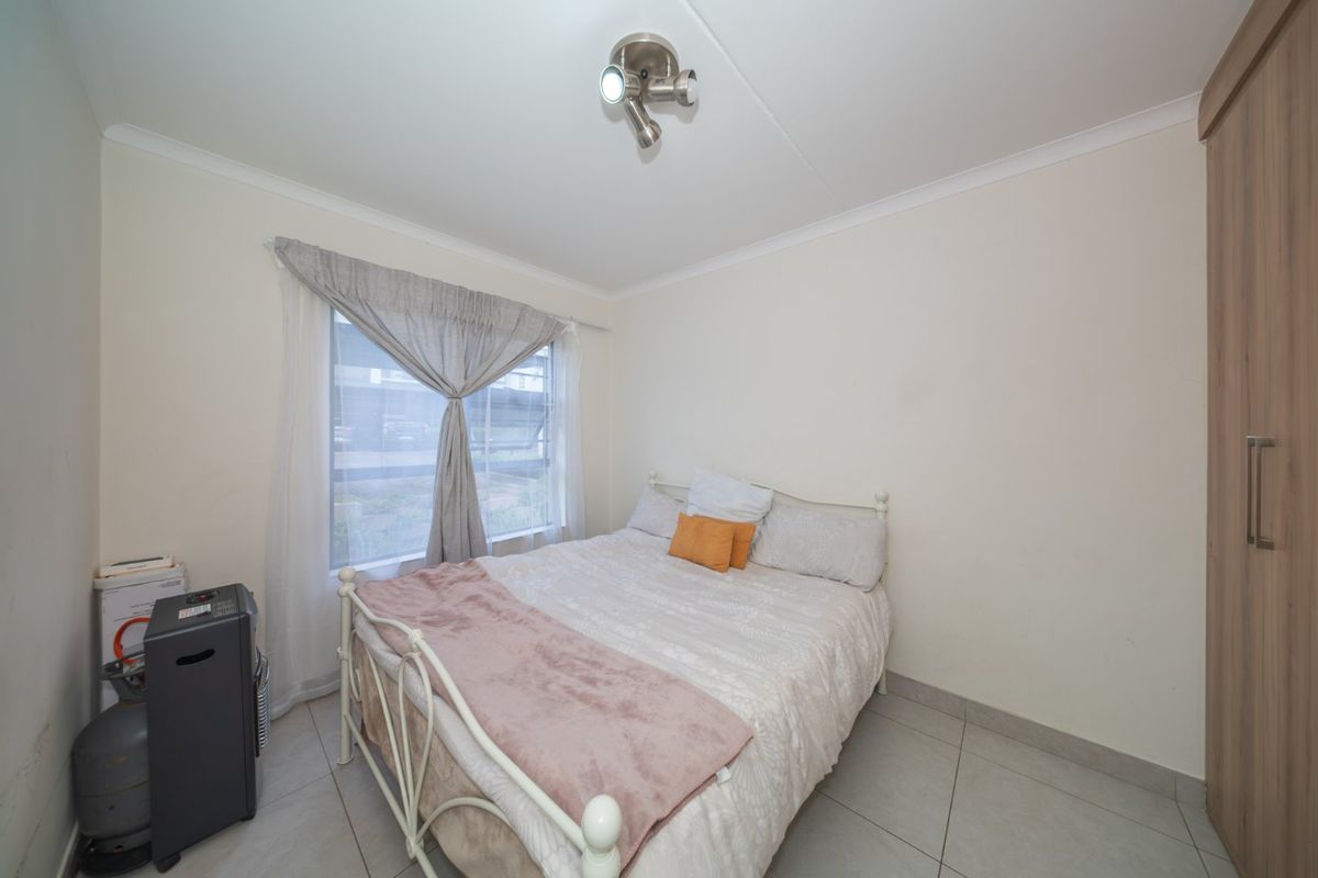 A functional bedroom featuring tiled flooring, a built-in wardrobe, and a ceiling-mounted spotlight fixture, providing a clean and practical living space.