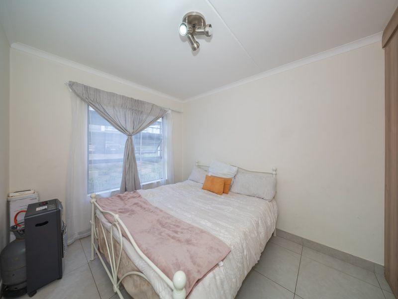 A functional bedroom featuring tiled flooring, a built-in wardrobe, and a ceiling-mounted spotlight fixture, providing a clean and practical living space.