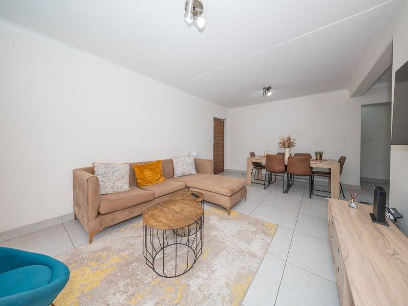 An open-plan living and dining area featuring neutral tiled flooring, clean white walls, and modern ceiling lighting, creating a bright and functional living space.