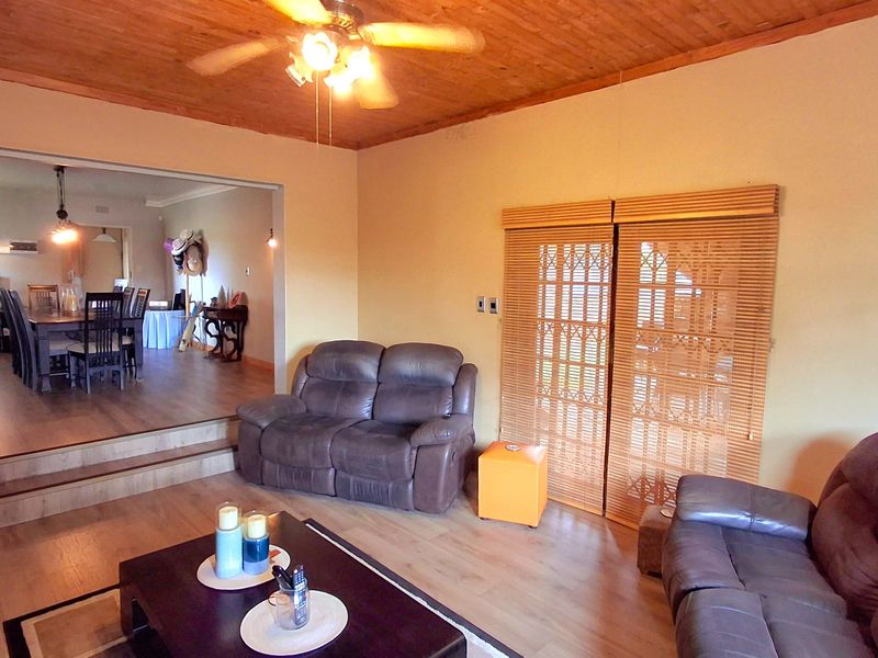 Open plan living area featuring timber ceilings, laminate flooring, and sliding doors leading to an outdoor space, with an adjacent dining area.