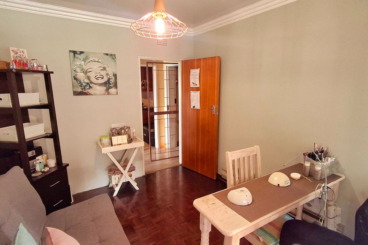 A multi-purpose room featuring parquet flooring, crown molding, and a secure entrance door, currently utilized as a workspace.