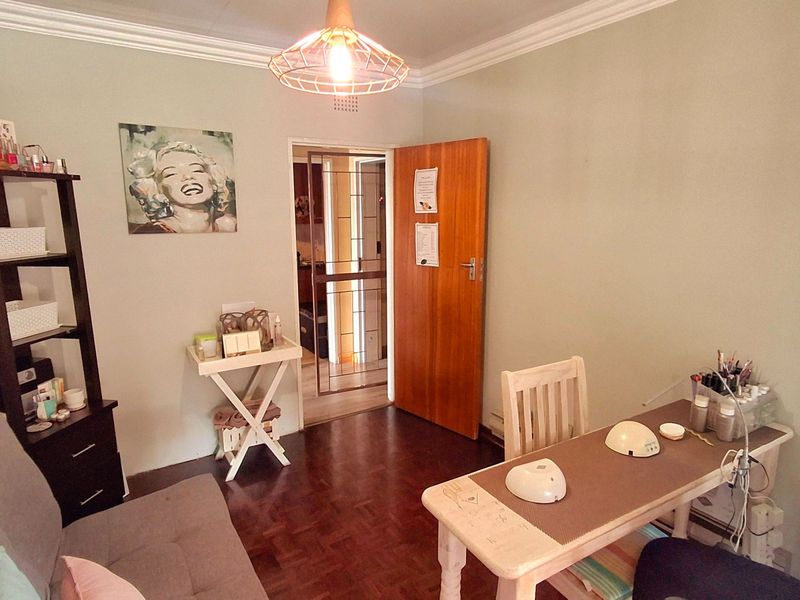 A multi-purpose room featuring parquet flooring, crown molding, and a secure entrance door, currently utilized as a workspace.