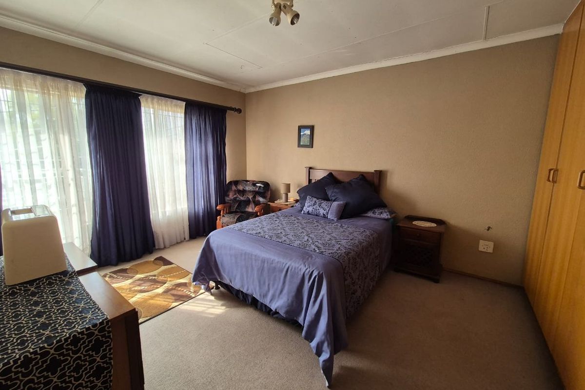 A spacious bedroom featuring neutral walls, carpeted flooring, and built-in wooden cupboards, offering a functional and comfortable living space.