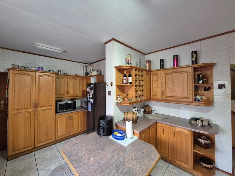 A functional kitchen featuring traditional wooden cabinetry, tiled backsplash, and laminate countertops, offering a classic layout with ample storage space.