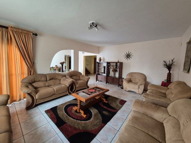 Spacious living room featuring tiled flooring and a distinctive architectural archway leading to adjacent areas, providing a comfortable and functional living space.