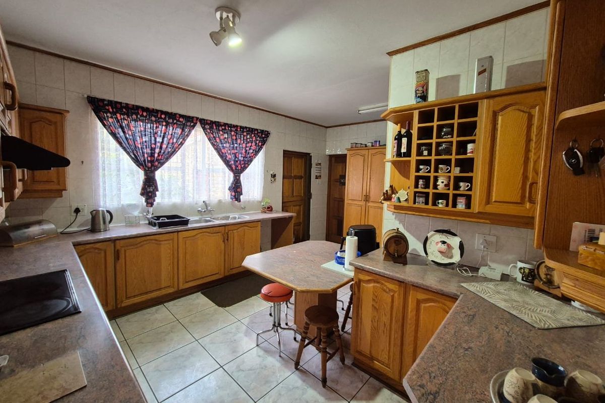 A functional kitchen featuring traditional wooden cabinetry, laminate countertops, tiled flooring, and a built-in wine rack, offering a classic layout with ample storage.