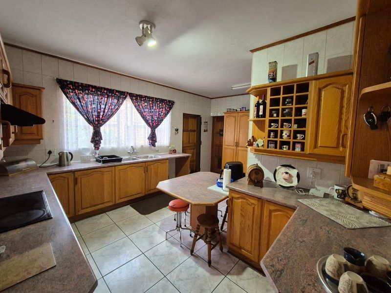 A functional kitchen featuring traditional wooden cabinetry, laminate countertops, tiled flooring, and a built-in wine rack, offering a classic layout with ample storage.