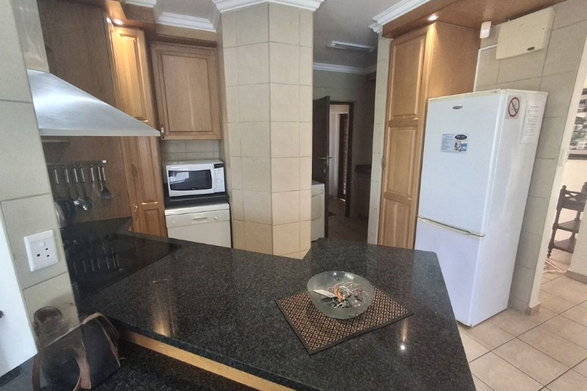 A functional kitchen featuring granite countertops, ample built-in cabinetry, and tiled finishes, offering a practical layout for daily meal preparation.