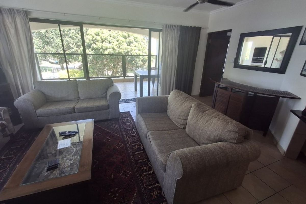 Spacious living room featuring tiled flooring, a ceiling fan, and large sliding glass doors providing access to an outdoor balcony area.