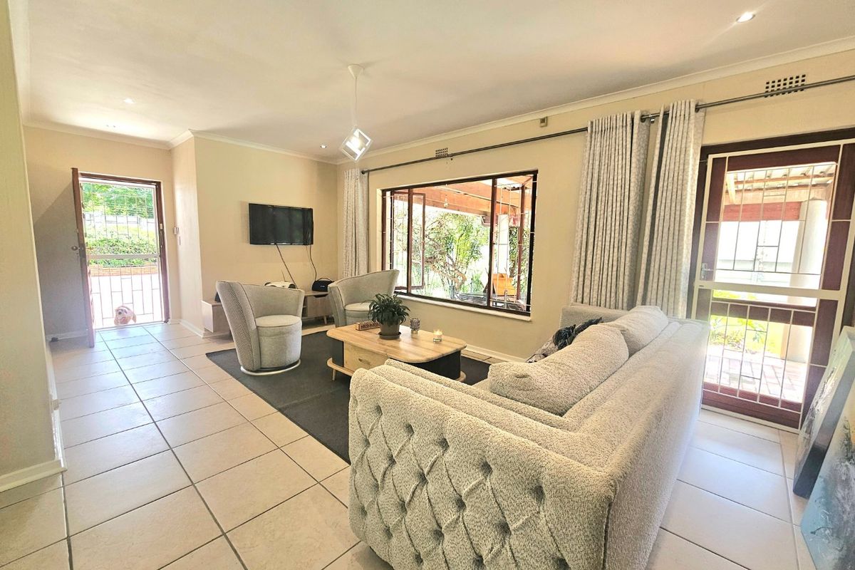 A bright and spacious living room featuring tiled flooring, recessed lighting, and direct access to the outdoor area through a secure sliding door.