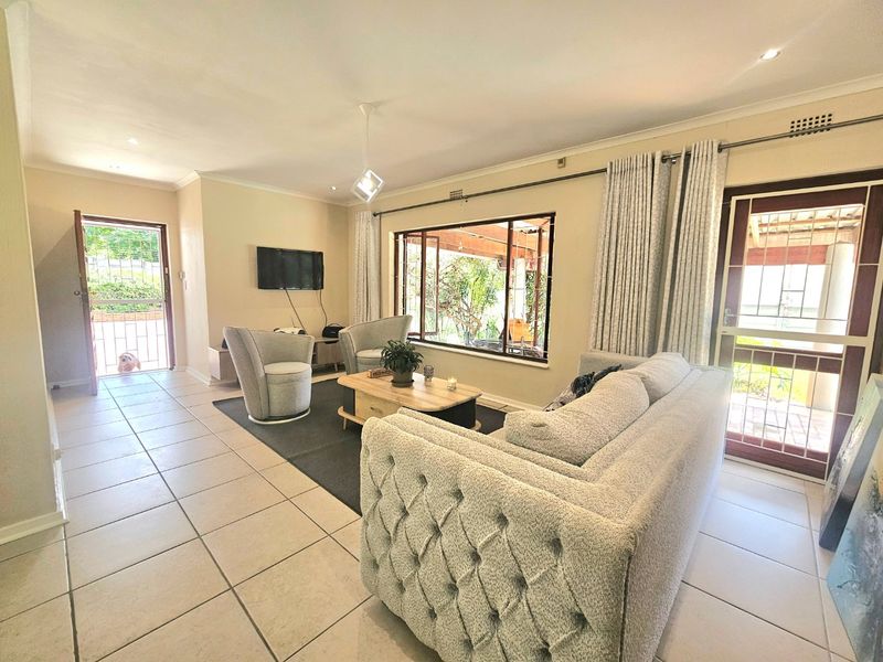 A bright and spacious living room featuring tiled flooring, recessed lighting, and direct access to the outdoor area through a secure sliding door.