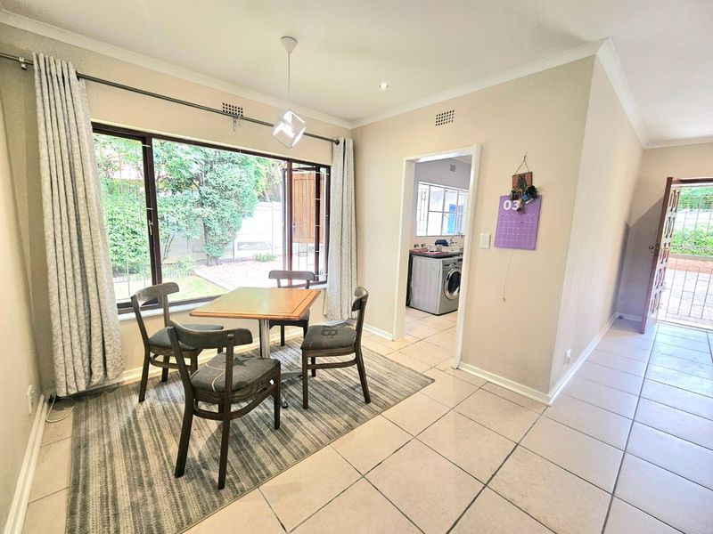 Open plan dining area featuring tiled flooring, large windows with garden views, and direct access to the adjacent laundry room.