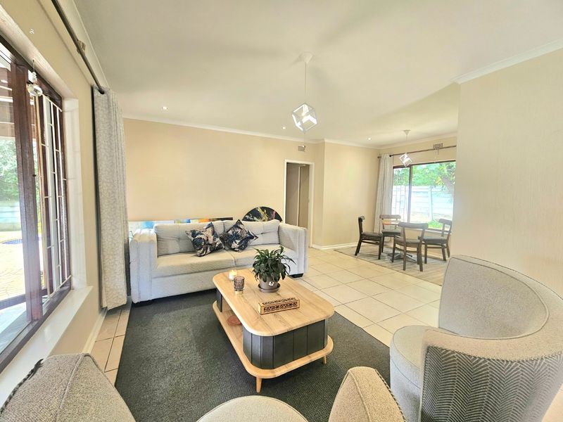 Spacious open-plan living and dining area featuring neutral tiled flooring, recessed lighting, and large sliding glass doors providing natural light and garden access.