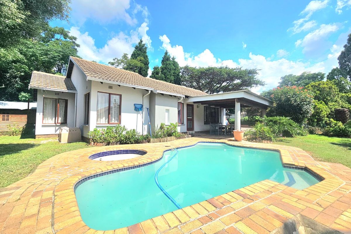 Rear view of the property featuring a swimming pool with integrated spa, a covered patio area, and a well-maintained garden.