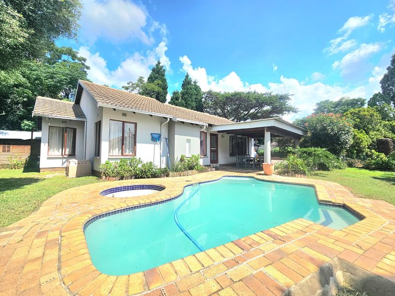 Rear view of the property featuring a swimming pool with integrated spa, a covered patio area, and a well-maintained garden.