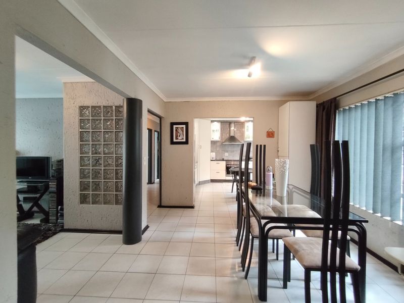 Open plan dining area featuring ceramic floor tiles and a decorative glass block wall, with a view through to the kitchen.