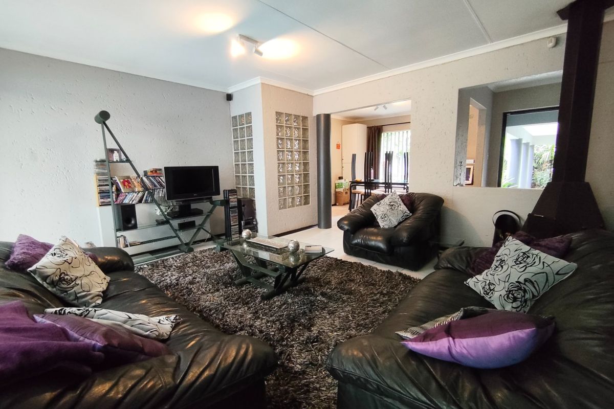 Spacious living room featuring a freestanding fireplace, textured walls, and a unique glass block partition, offering an open-plan flow to the dining area.
