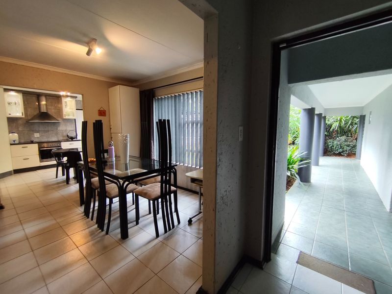 Open plan dining and kitchen area featuring tiled floors, built-in cabinetry, and direct access to a covered outdoor patio space.
