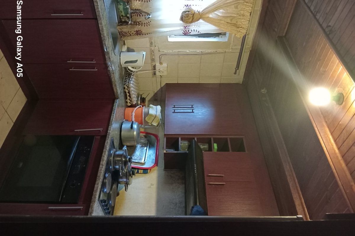 A dated kitchen featuring dark wood cabinetry, built-in oven and hob, and a timber ceiling, requiring cosmetic updates to modernize the space.