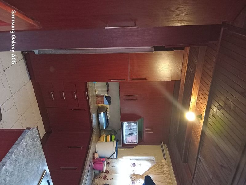 A dated kitchen featuring dark wood cabinetry, timber ceiling panels, and laminate countertops, requiring modernization to improve functionality and aesthetic appeal.
