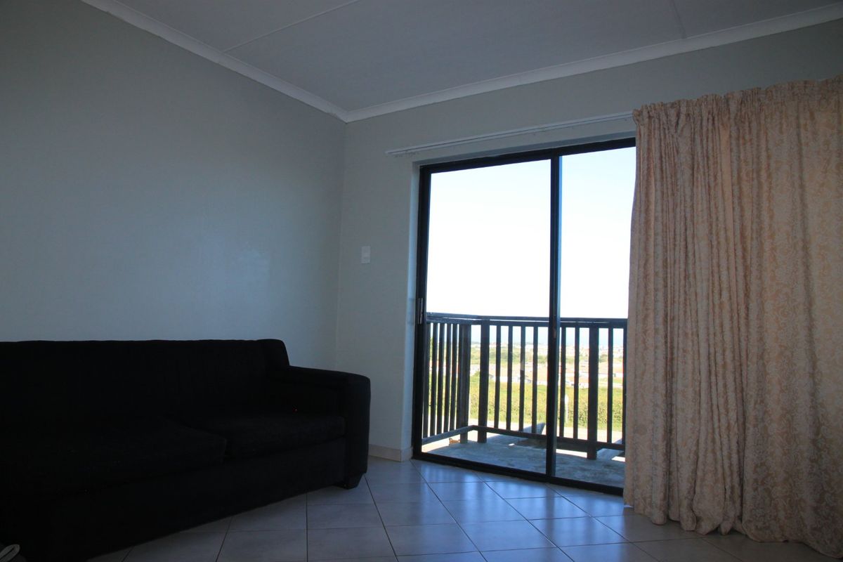 A living room featuring tiled flooring and a sliding glass door that provides access to an outdoor balcony area.